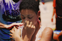 A girl holding her nose as she is baptized.