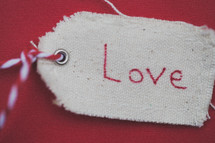 A Christmas gift tag reading "Love," on a red background.