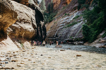 people hiking through a river 