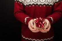 a man in a sweater holding a Christmas gift box 