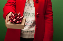a woman in a red coat giving a gift at Christmas 