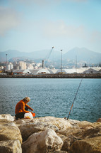 fisherman fishing along a rocky shore 