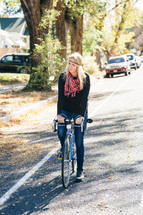 woman riding a bicycle down a neighborhood street 