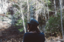 a man with long hair standing in the woods 