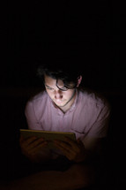 Light shining on a man from an electronic tablet.