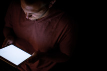 A man holding and being illuminated by an electronic tablet.