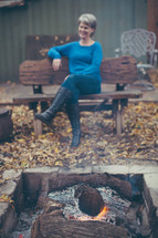 a woman sitting by a fire pit 