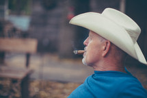 a man in a cowboy hat smoking a cigar 