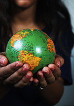 a woman holding a globe in her hands 
