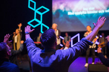 a man with raised hands at a worship service praising God 