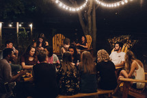 friends gathered around a table talking at a dinner party 