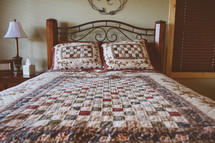 A full size bed covered in a colorful quilt.