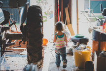 a little girl getting tools in a garage 