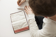 Writing in a journal while reading the Bible.