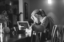 a woman sitting at a table working and writing with a laptop and coffee cup 