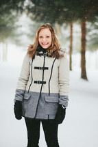 a woman in a coat standing in the snow 