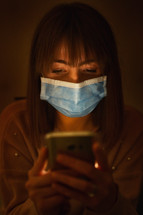 a woman wearing a face mask looking at a cellphone screen 