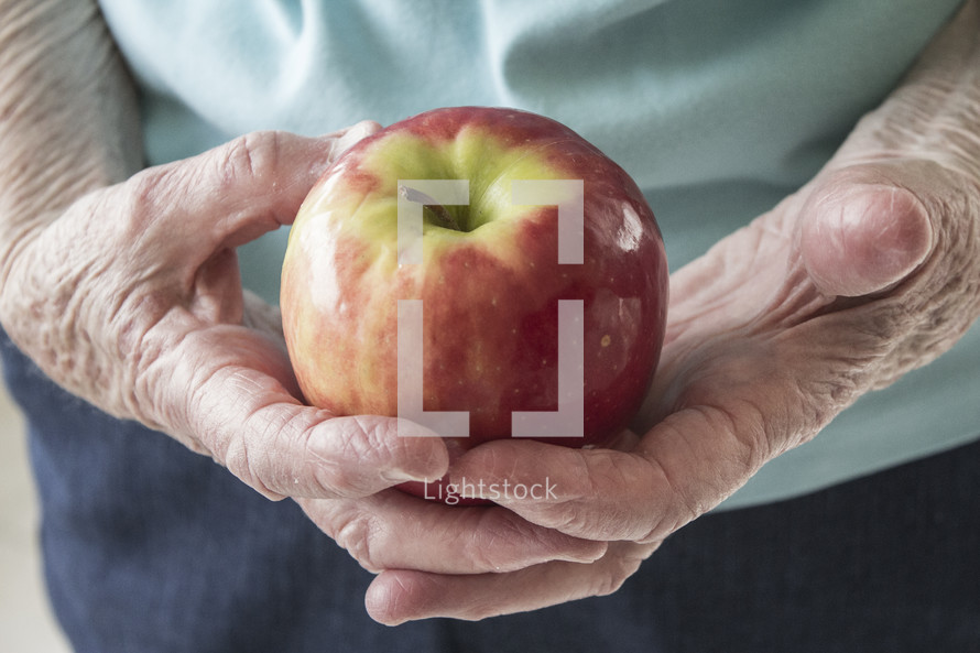 elderly woman holding an apple