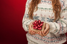 a woman in a sweater holding a gift box 