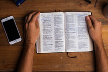 man reading a Bible and cellphone
