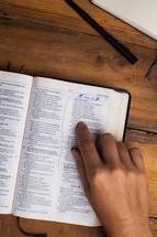 man reading a Bible and pointing to scripture 