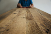 man reading a Bible at the end of a table 
