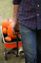 a man pulling a wagon full of pumpkins 