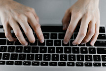 hands typing on a laptop computer 