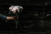arm of a woman holding out a bouquet of flowers 