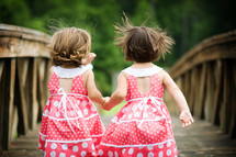 sisters holding hands in matching dresses 