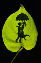 Conceptual Silhouette Of Romantic Couple Embracing holding an umbrella