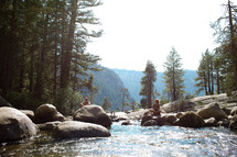 sitting on rocks by a stream in Yosemite 