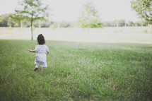 Girl walking through a grassy field.