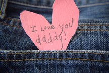 I love you daddy note on a pink paper heart in a jeans pocket