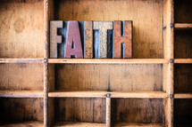 Wooden letters spelling "faith" on a wooden bookshelf.