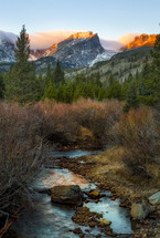 sunlight on mountain peaks and a stream 