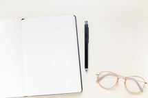 notebook, pen, and reading glasses 
