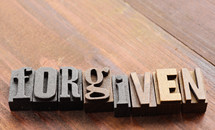 The word "forgiven" spelled out with old letter press letters.