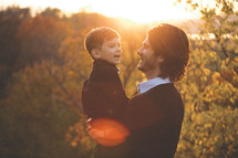 father holding his son outdoors under sunlight