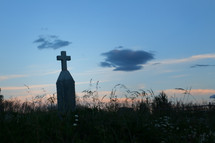 cross on a tombstone at sunset 