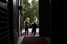 siblings holding hands walking through a doorway 