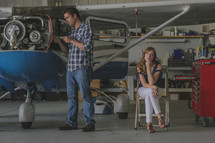 a man working on an airplane and an annoyed woman