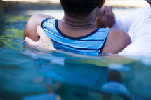 Man being baptized in a pool of water.