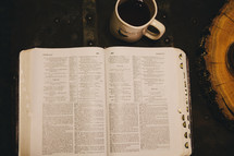 An open Bible and a coffee mug. 