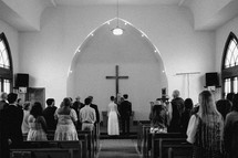 Black and white photo of a wedding ceremony inside small church.