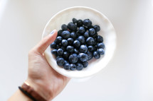hand holding a bowl of blueberries 