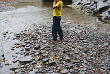 a barefoot boy skipping rocks in a stream 
