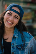 A smiling young woman with her cap on backwards.
