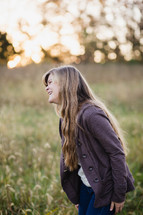 a girl standing in a field of tall grass laughing 