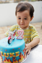 Cute Asian toddler boy blowing the candle on his cake